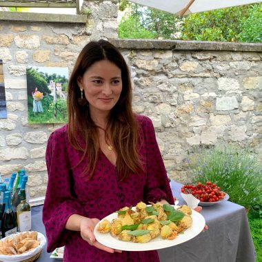 Mimi Thorisson holding a dish she cooked, wearing a Mirae dress